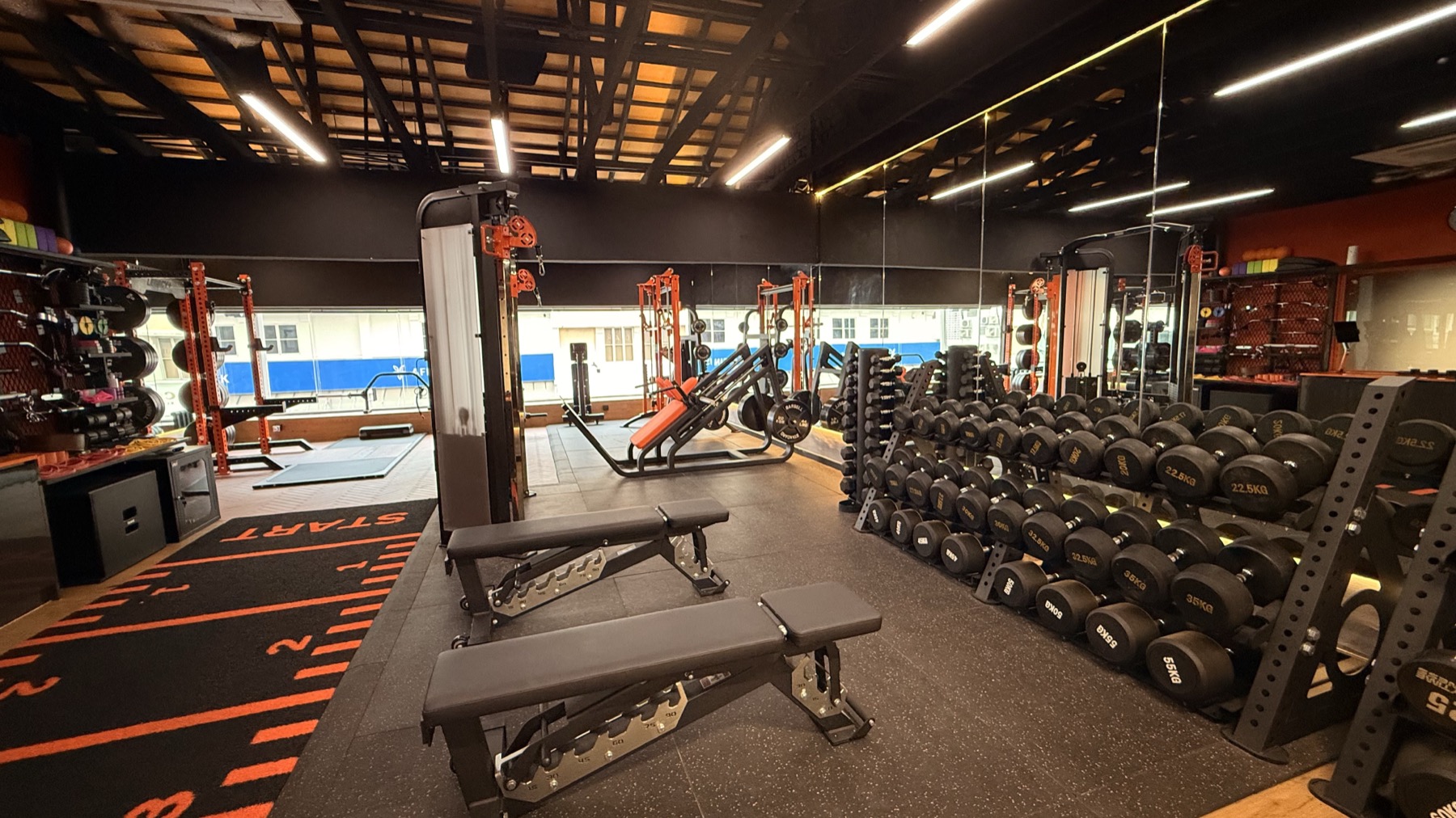 Free weight area at LEGACY+ with benches, dumbbells, and mirrored strength floor.